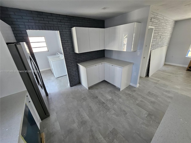 kitchen with modern cabinets, brick wall, white cabinets, and light countertops