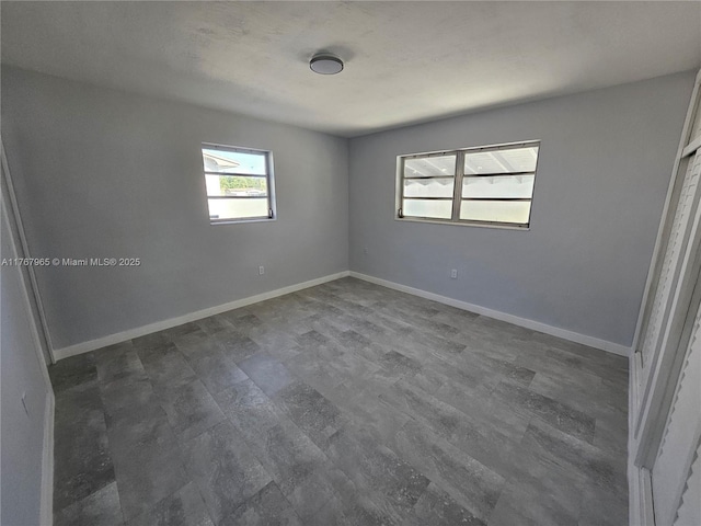 spare room with baseboards and dark wood-style flooring