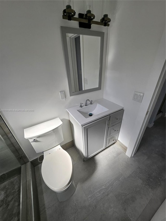 bathroom featuring toilet, vanity, and baseboards