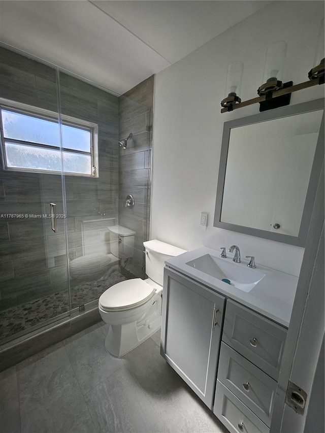 full bathroom featuring a stall shower, toilet, and vanity