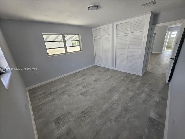 unfurnished bedroom with wood finished floors, baseboards, and visible vents