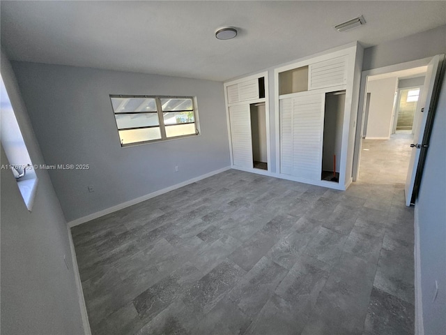 unfurnished bedroom featuring visible vents, two closets, and baseboards