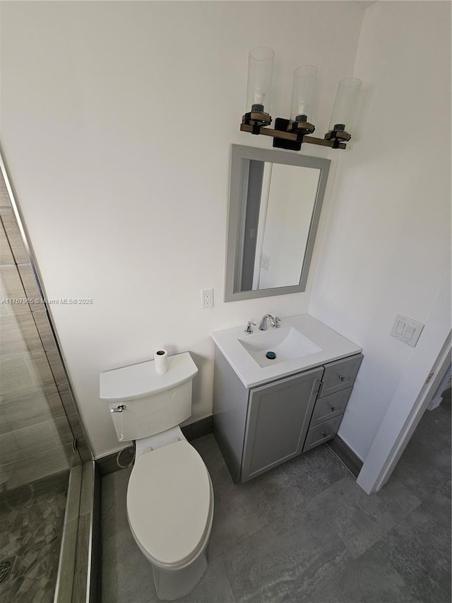 bathroom with toilet, vanity, and baseboards