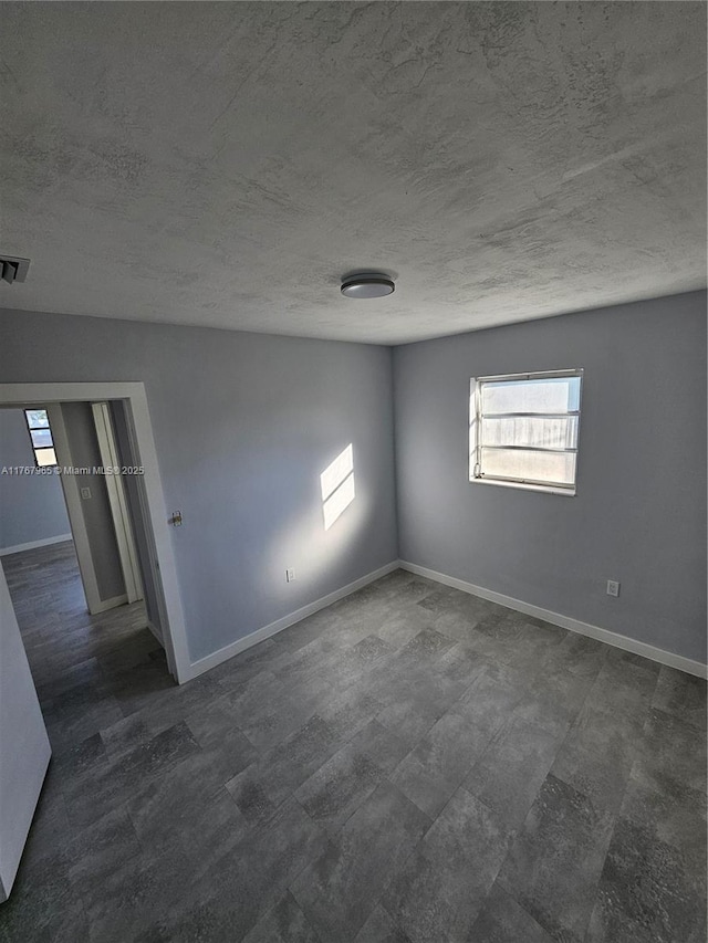 unfurnished room featuring visible vents, a textured ceiling, dark wood-type flooring, and baseboards