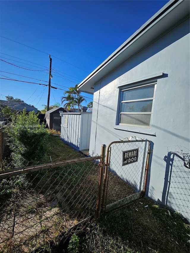 view of side of property with a gate, stucco siding, and fence