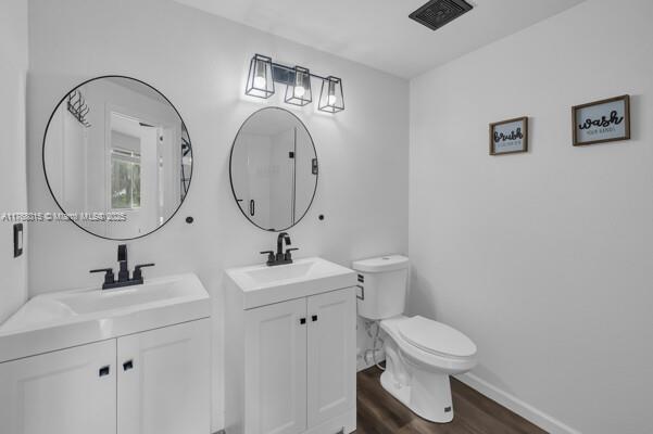 7833 Sanibel Dr Unit 7833, Tamarac, FL 33321 - bathroom featuring wood finished floors, toilet, two vanities, and a sink