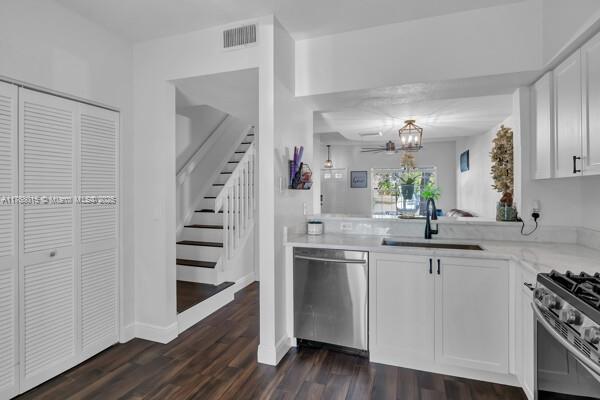 7833 Sanibel Dr Unit 7833, Tamarac, FL 33321 - kitchen featuring visible vents, a sink, stainless steel appliances, white cabinets, and dark wood-style flooring