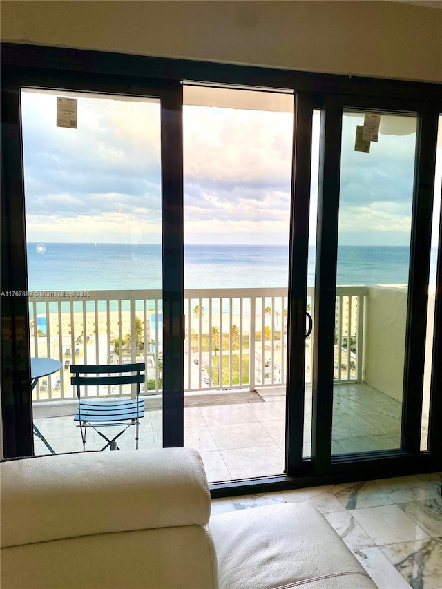 entryway featuring marble finish floor, a view of the beach, and a water view