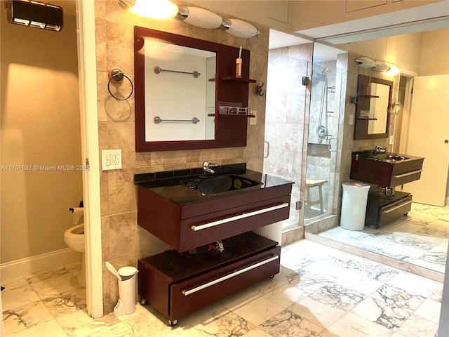 full bathroom with toilet, vanity, a stall shower, marble finish floor, and tile walls