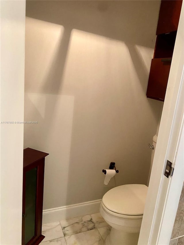 bathroom with baseboards, toilet, and marble finish floor