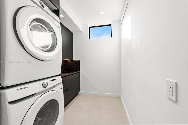 2572 NE 182nd Ter, North Miami Beach, FL 33160 - laundry area featuring light tile patterned floors, stacked washer / dryer, cabinet space, and baseboards