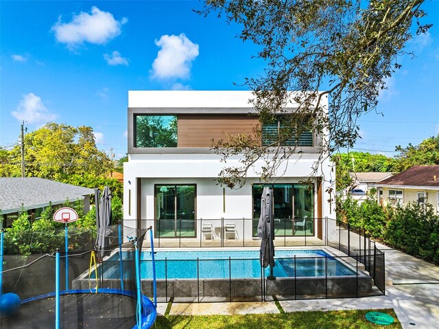 2572 NE 182nd Ter, North Miami Beach, FL 33160 - rear view of property featuring a fenced in pool, a trampoline, fence, stucco siding, and a patio area
