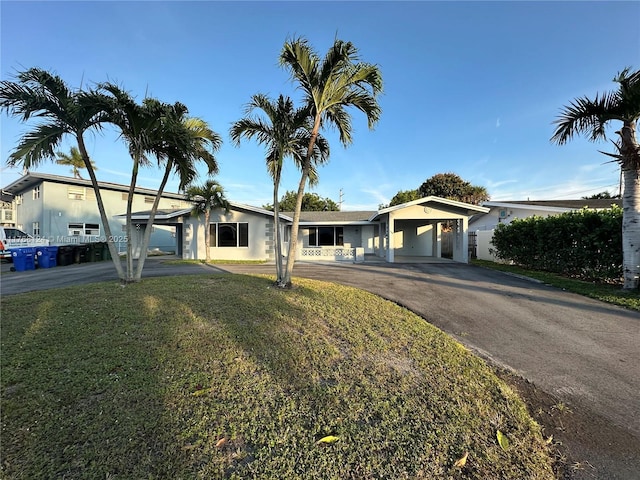 view of front facade featuring stucco siding, a front lawn, an attached carport, and driveway
