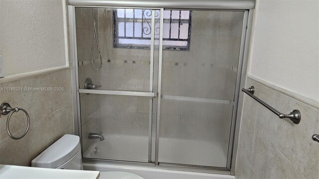 13715 Kendale Lakes Cir Unit A-201, Miami, FL 33183 - bathroom featuring toilet, enclosed tub / shower combo, wainscoting, and tile walls