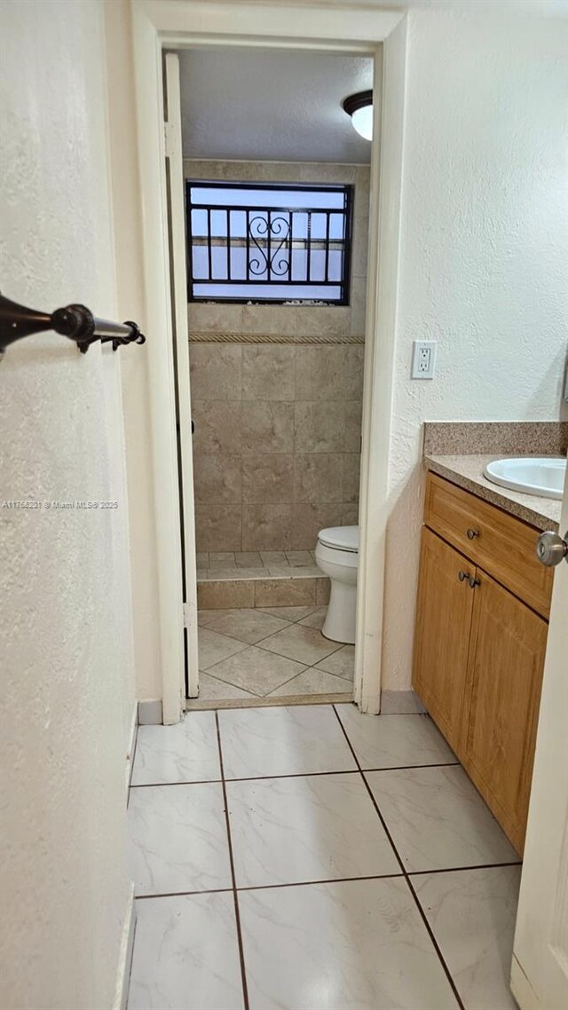 13715 Kendale Lakes Cir Unit A-201, Miami, FL 33183 - bathroom featuring vanity, toilet, a textured wall, and marble look tiles
