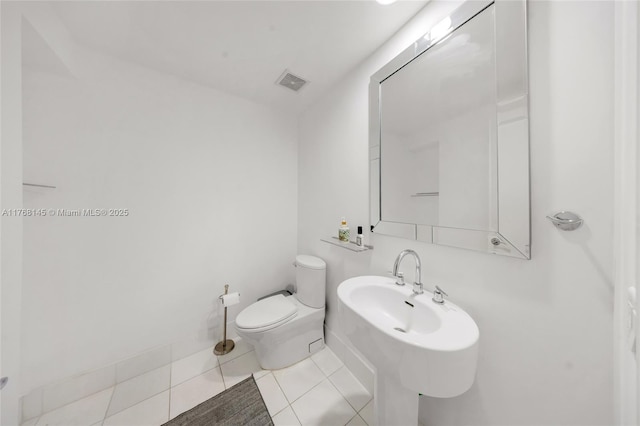 half bath featuring tile patterned floors, toilet, and visible vents