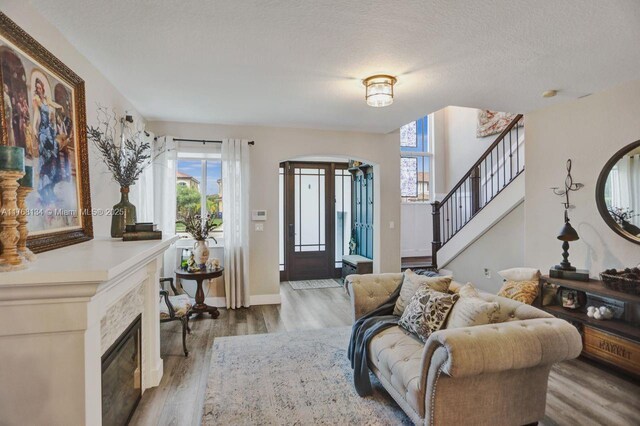 living room with wood finished floors, baseboards, arched walkways, stairs, and a textured ceiling