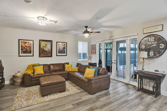 living area featuring baseboards, a textured ceiling, wood finished floors, and a ceiling fan
