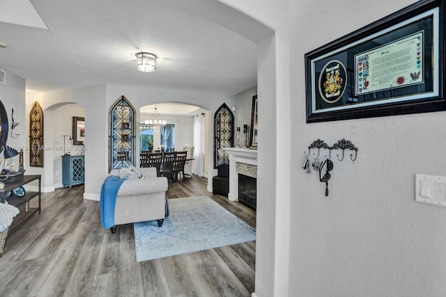 living room with baseboards, arched walkways, an inviting chandelier, and wood finished floors