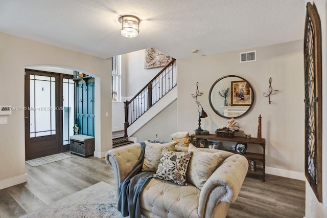 foyer featuring arched walkways, visible vents, stairway, and wood finished floors