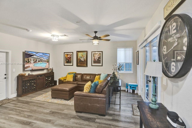living room with ceiling fan, visible vents, baseboards, and wood finished floors