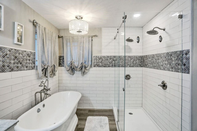 full bathroom with a shower stall, a freestanding tub, wood finished floors, and tile walls