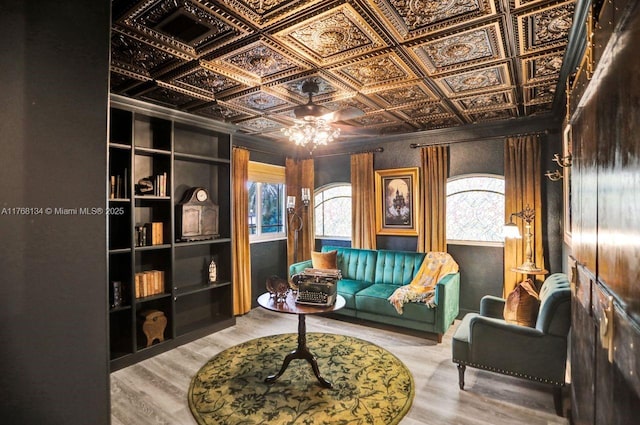 living area with wood finished floors, an ornate ceiling, and ceiling fan