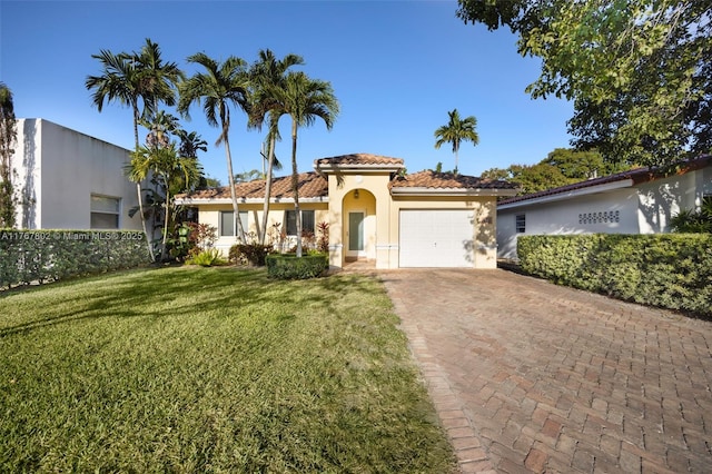 mediterranean / spanish house with a front lawn, a tiled roof, stucco siding, decorative driveway, and an attached garage