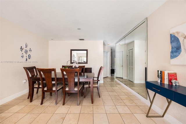 dining area with light tile patterned floors, visible vents, and baseboards