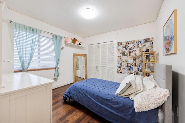 bedroom with dark wood finished floors, baseboards, and a closet