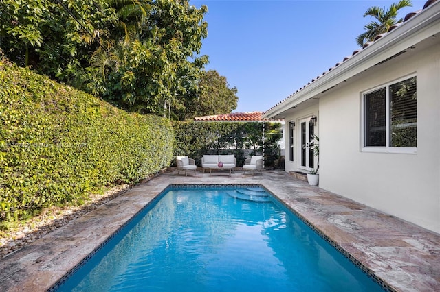 view of pool with an outdoor living space, a fenced in pool, french doors, a fenced backyard, and a patio area
