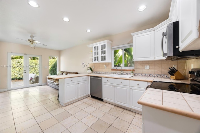 kitchen featuring a ceiling fan, a sink, tile countertops, appliances with stainless steel finishes, and a peninsula