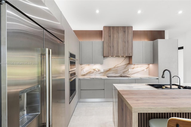 2523 Red Rd, Coral Gables, FL 33134 - kitchen with high end refrigerator, modern cabinets, a sink, black electric cooktop, and recessed lighting