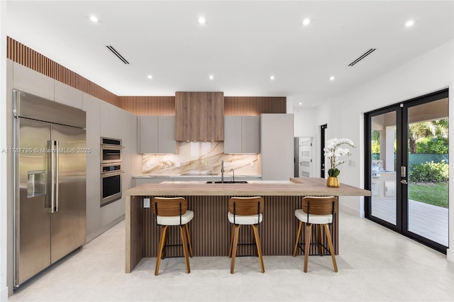 2523 Red Rd, Coral Gables, FL 33134 - kitchen with appliances with stainless steel finishes, a large island, gray cabinets, a breakfast bar area, and recessed lighting