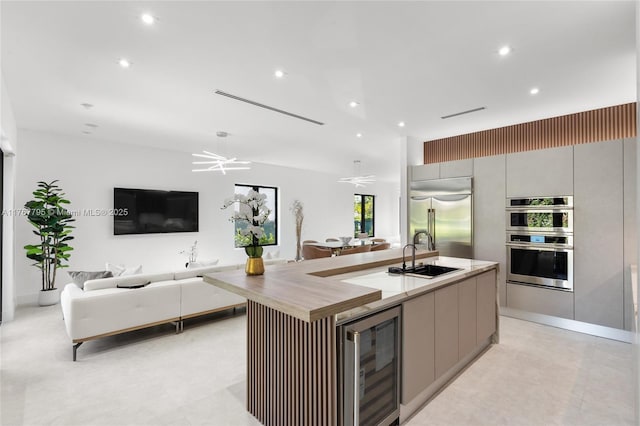 2523 Red Rd, Coral Gables, FL 33134 - kitchen with a sink, appliances with stainless steel finishes, beverage cooler, modern cabinets, and an island with sink