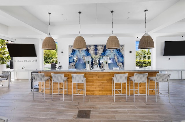 kitchen featuring a wealth of natural light, decorative light fixtures, a kitchen bar, and wood tiled floor