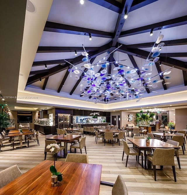 dining area with light wood-type flooring, beamed ceiling, high vaulted ceiling, and an inviting chandelier