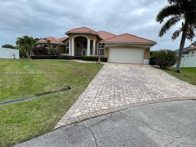 mediterranean / spanish-style house with a tile roof, stucco siding, decorative driveway, a front lawn, and a garage
