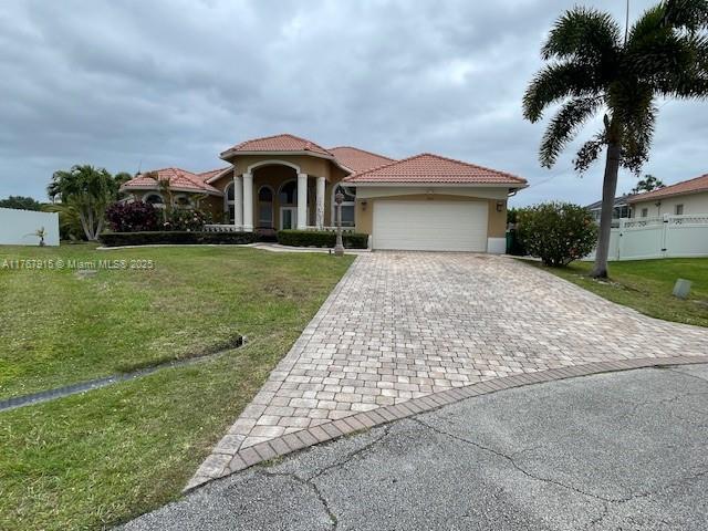mediterranean / spanish-style house with a tile roof, a front yard, stucco siding, decorative driveway, and a garage