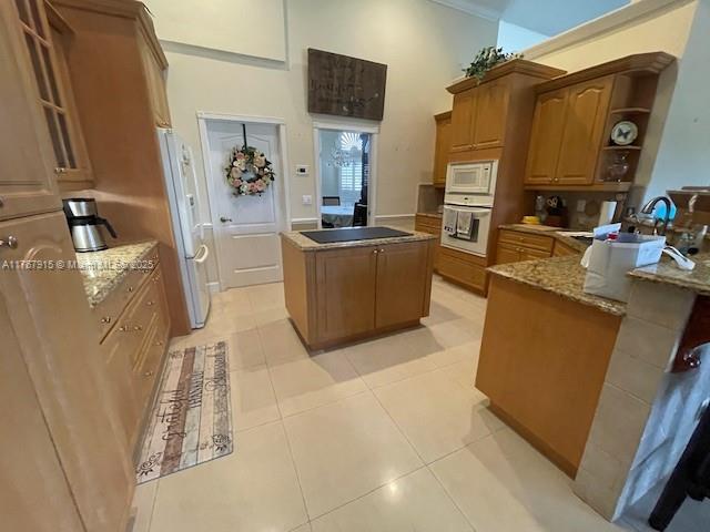 kitchen featuring open shelves, white appliances, light tile patterned floors, a kitchen island, and stone countertops