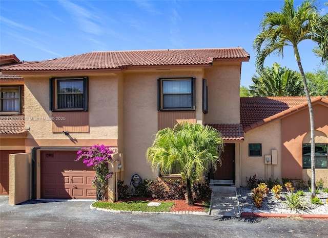 view of front facade featuring stucco siding, driveway, an attached garage, and a tiled roof