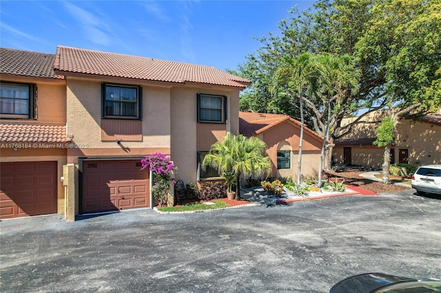 view of front facade featuring stucco siding, a tiled roof, an attached garage, and driveway