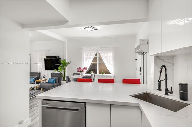 kitchen featuring light stone counters, visible vents, a sink, white cabinetry, and open floor plan