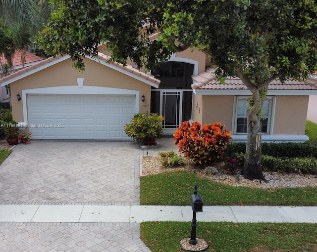 12067 Tevere Dr, Boynton Beach, FL 33437 - view of front facade featuring decorative driveway, a tile roof, an attached garage, and stucco siding