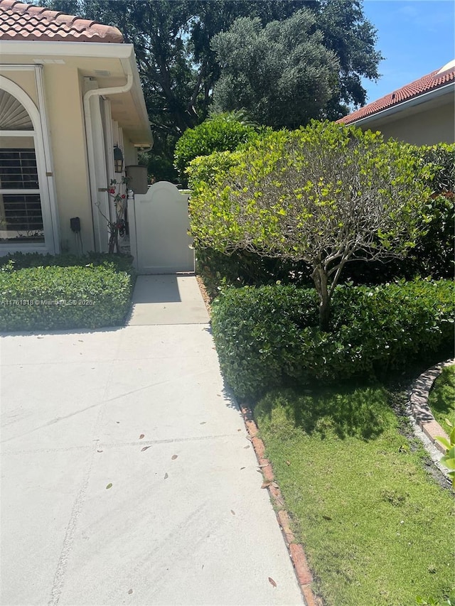 view of home's exterior featuring a tile roof, a gate, and stucco siding