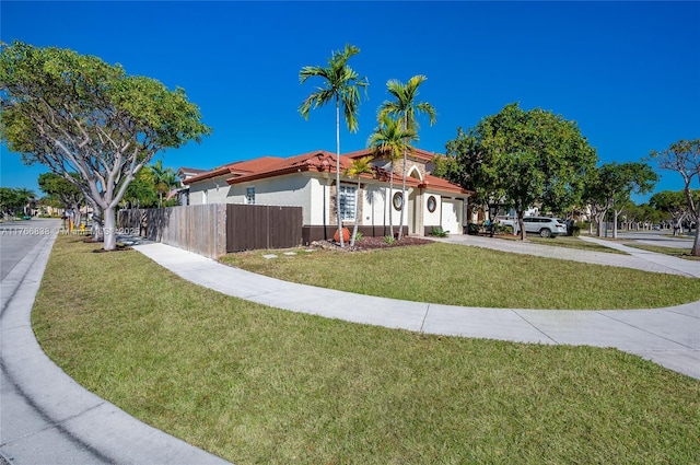 view of front facade with stucco siding, a front lawn, driveway, fence, and a garage