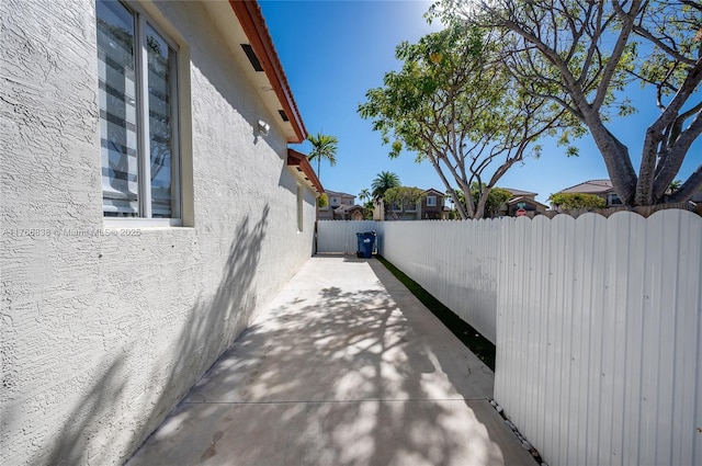 view of side of home featuring stucco siding, fence private yard, and a patio
