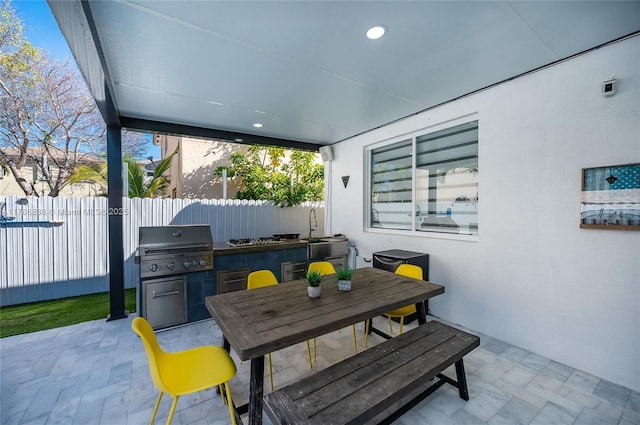 view of patio / terrace with grilling area, a sink, outdoor dining area, and fence