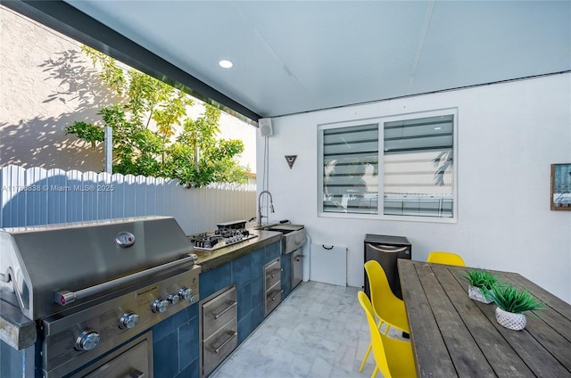 view of patio / terrace featuring a sink, an outdoor kitchen, a grill, and fence