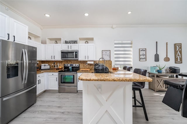 kitchen with white cabinets, appliances with stainless steel finishes, a kitchen bar, crown molding, and tasteful backsplash